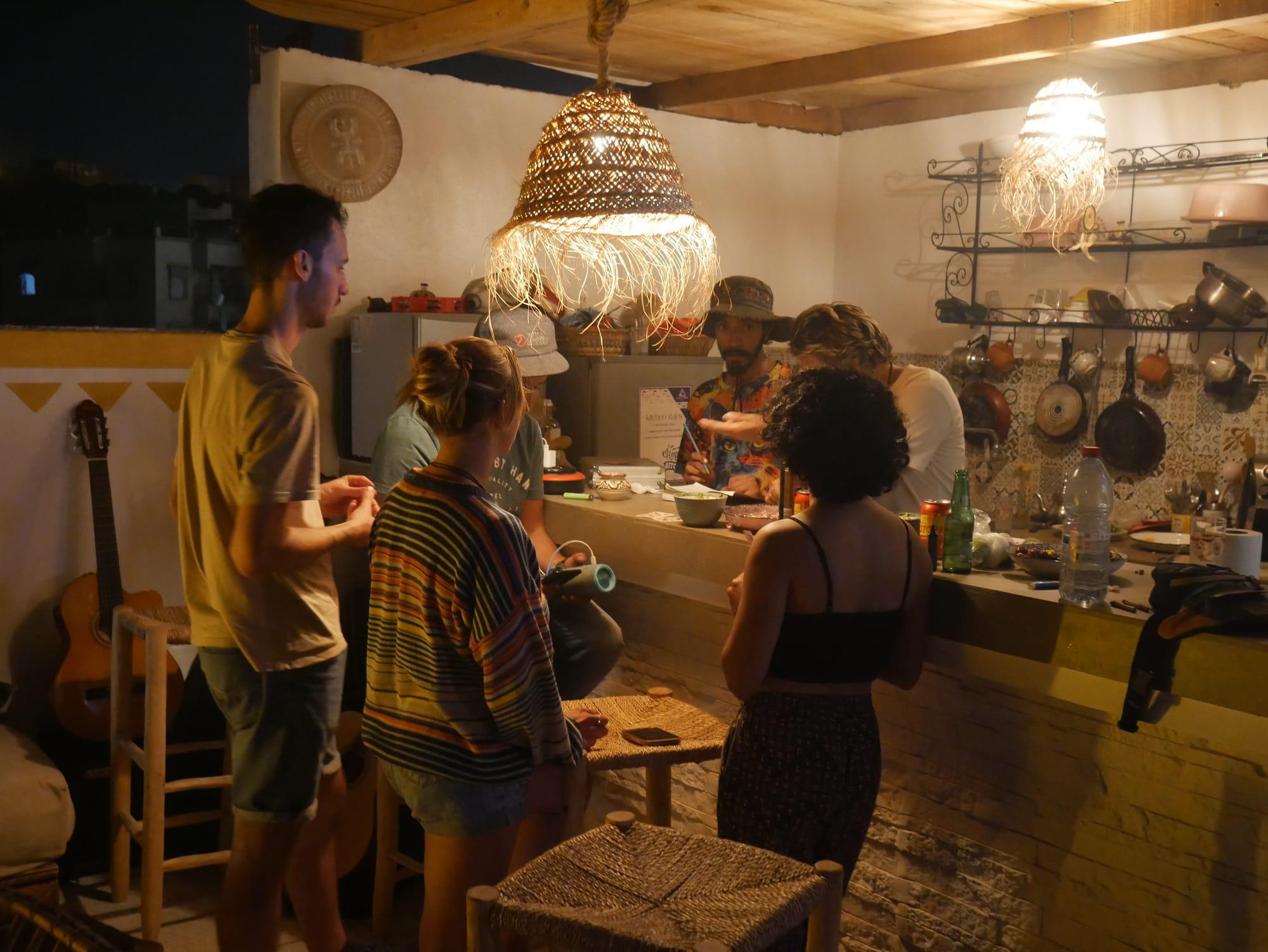 Abends in der Gemeinschaftsküche des Azul Berg Hostels bei Taghazout — Gäste kochen zusammen, Gitarren lehnen an der Wand